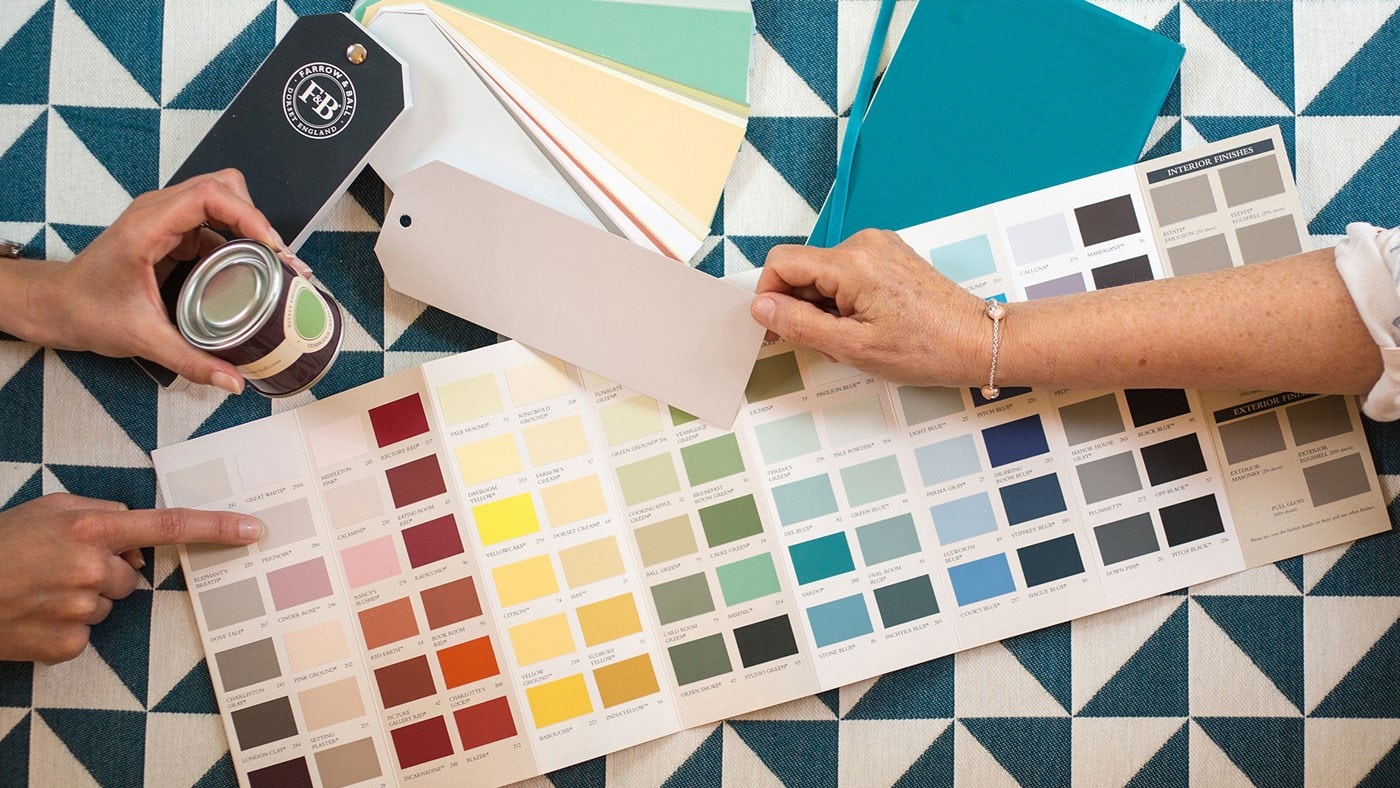 Farrow & Ball's Charlie Cosby and Joa Studholme discussing colour swatches in a white living room
