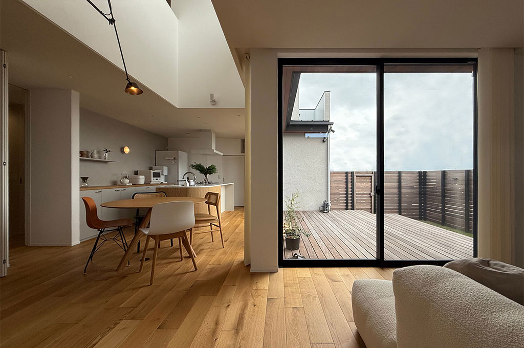 Farrow & Ballの柔らかなニュートラルカラーが包み込むリビング。無垢材のフローリングとテラスが繋がる開放的な空間で、高品質な塗料が生み出す奥行きのある壁色が、上質な家具や自然光と調和し、心安らぐ住まいを演出しています。