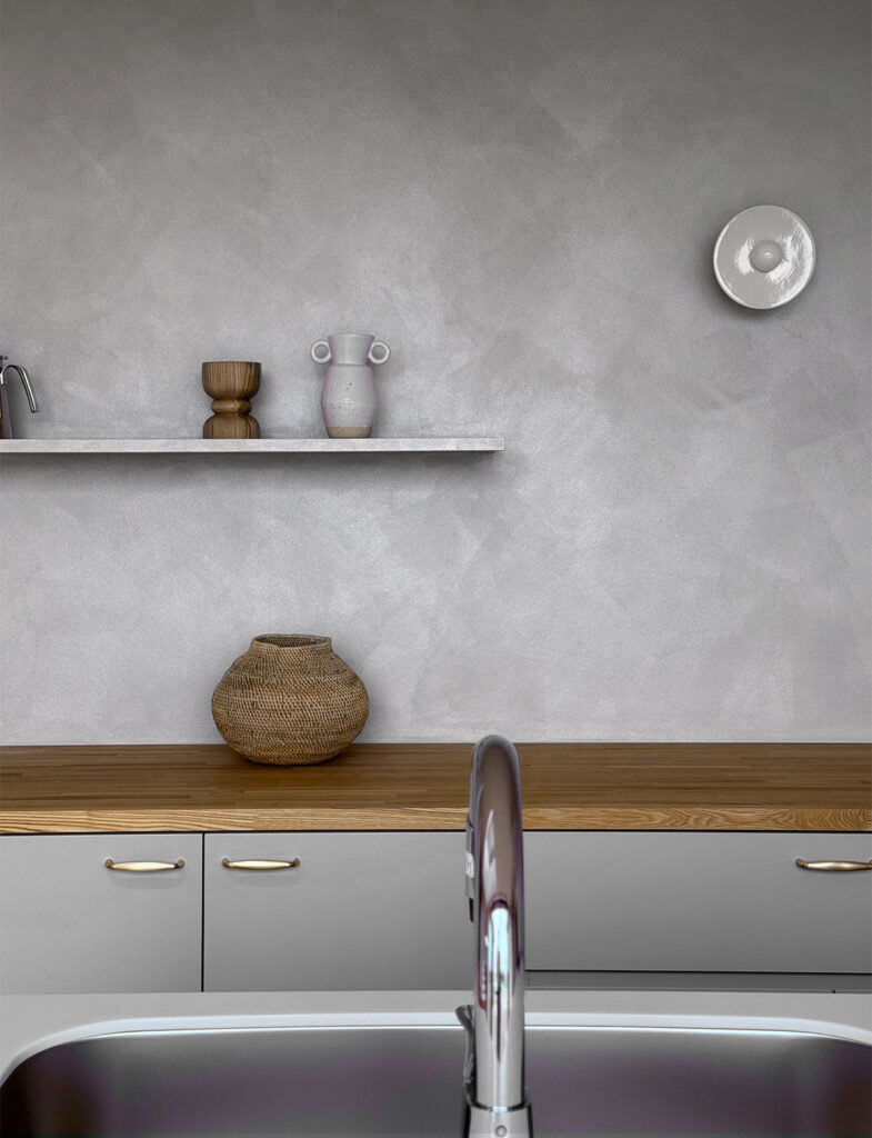 キッチン背面を彩る、「Moire（モアレ）」仕上げ。職人の手作り感のある意匠性と、繊細な光沢のあるメタリックな質感が、水回りにも安心の機能性とデザイン性を両立し、ディスプレイを引き立てる上質な壁面を実現しています。