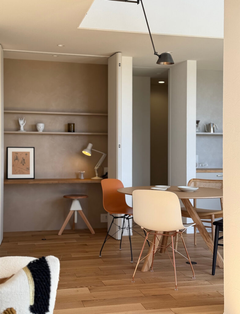 Moire（モアレ）の温かみのあるベージュで仕上げた書斎コーナーと、洗練された北欧家具が調和するダイニング。奥行きを感じさせるニュアンスカラーの壁面が、デスクライトの灯りに映え、日常を優雅に彩るモダンで心地よいインテリア空間を演出しています。