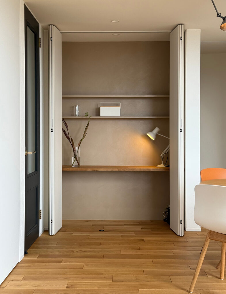 Moire（モアレ）の温かみのあるベージュで仕上げた書斎コーナーと、洗練された北欧家具が調和するダイニング。奥行きを感じさせるニュアンスカラーの壁面が、デスクライトの灯りに映え、日常を優雅に彩るモダンで心地よいインテリア空間を演出しています。