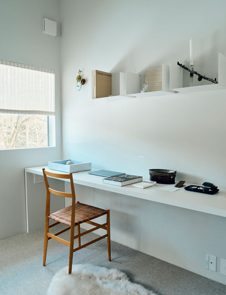インテリアスタイリスト・黒田美津子さんのアトリエにあるワークスペース。白い壁に溶け込むフロートタイプのデスクとシェルフが、浮遊感のある軽やかな空間を演出している。ジオ・ポンティの名作「スーパーレッジェーラ」を思わせる繊細なチェアが置かれ、窓からの柔らかな光と影が、ディスプレイされた本やキャンドルの陰影を美しく描き出す、思考を深めるためのスタイリング。