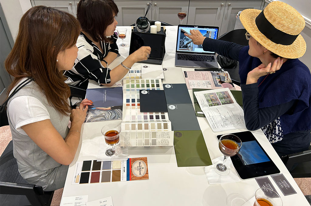インテリアスタイリスト・黒田美津子さんのアトリエに使う色の打ち合わせ風景。テーブルには多数のカラーチップや素材サンプル、デザイン雑誌が広げられ、FARROW&BALLのプロのカラースタイリストに相談している。