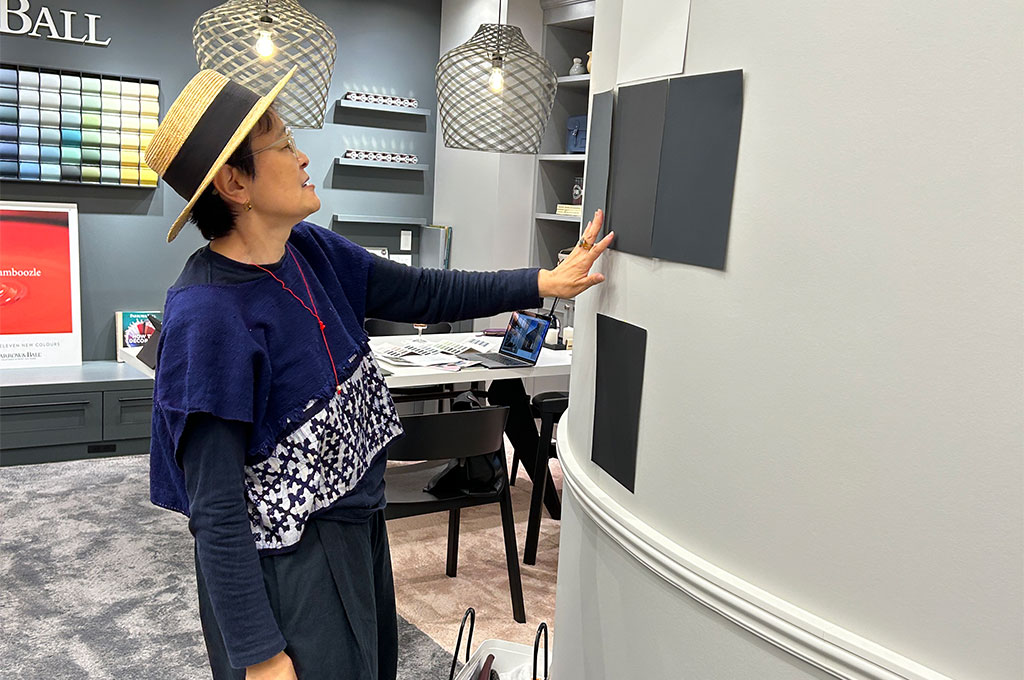 インテリアスタイリスト・黒田美津子さんのアトリエに使う色の打ち合わせ風景。テーブルには多数のカラーチップや素材サンプル、デザイン雑誌が広げられ、FARROW&BALLのプロのカラースタイリストに相談している。