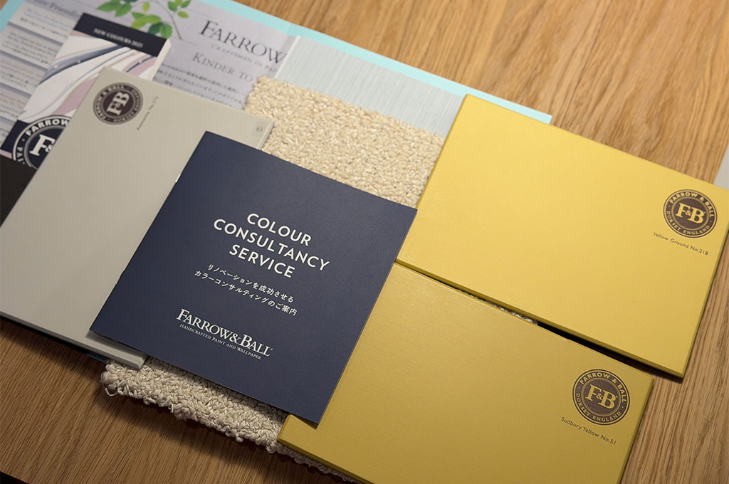 ザ・コンランショップ 新宿店のワークショップにて、Farrow & Ballの「No.218 Yellow Ground」などの明るいイエローやグレーのペイント板と、カラーコンサルタンシーサービスのパンフレット、白や淡いブルーのファブリックを組み合わせた寝室のカラーコーディネート。