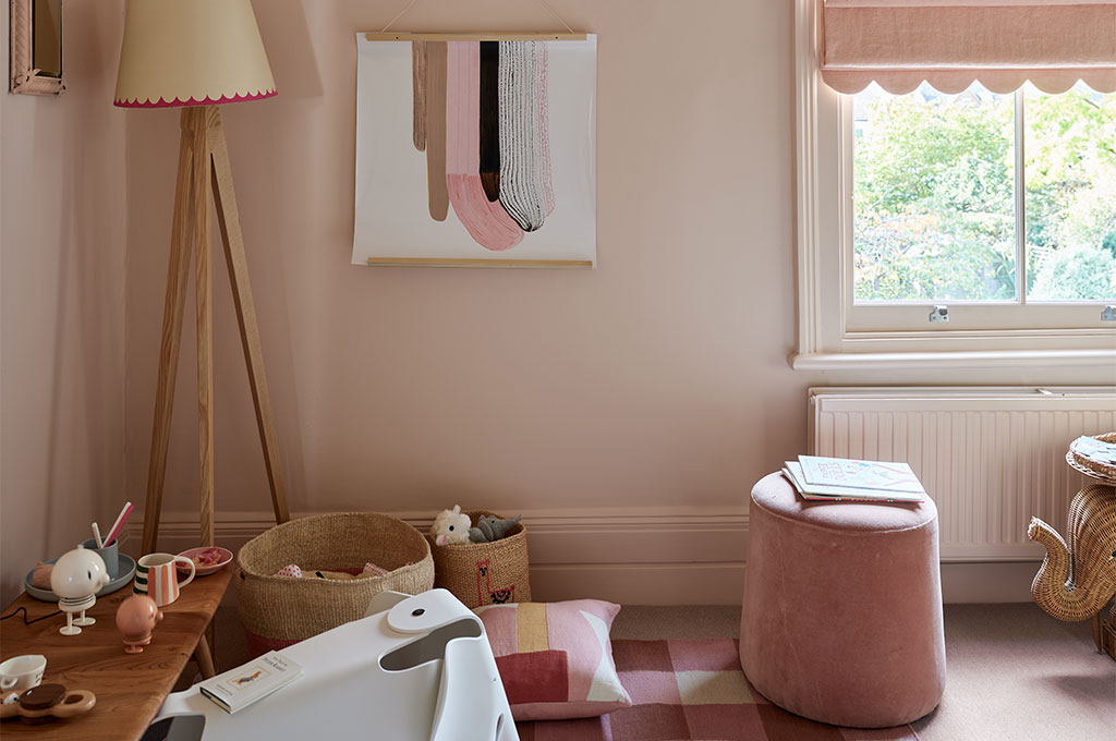 Farrow & Ballの優美なピンク「No.231 Setting Plaster」で壁と幅木を包み込んだカラードレンチングの子供部屋。ニュアンスあるピンクが上質な家具やアートと調和する、遊び心に満ちたモダンで愛らしいインテリア空間。